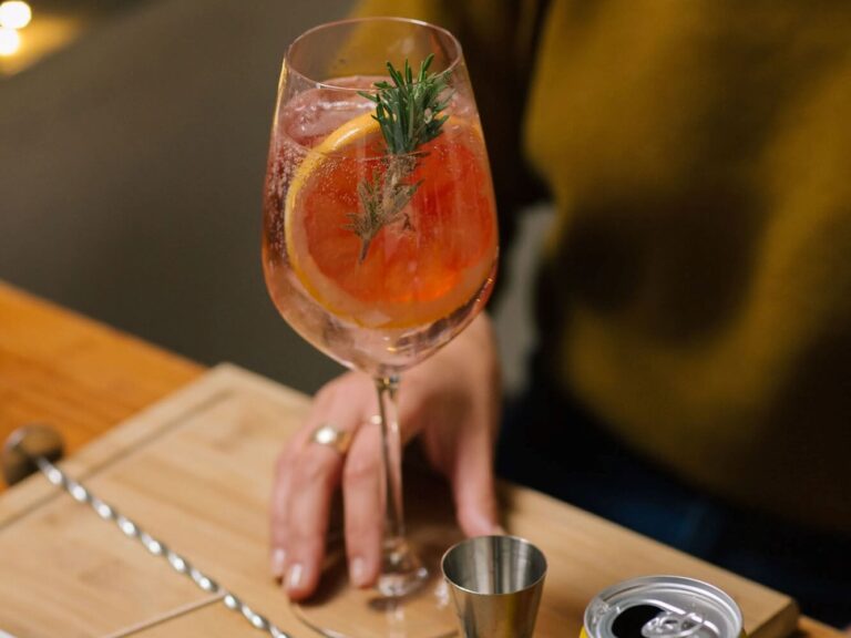 Cocktail garnished with a rosemary branch and a slice of grapefruit